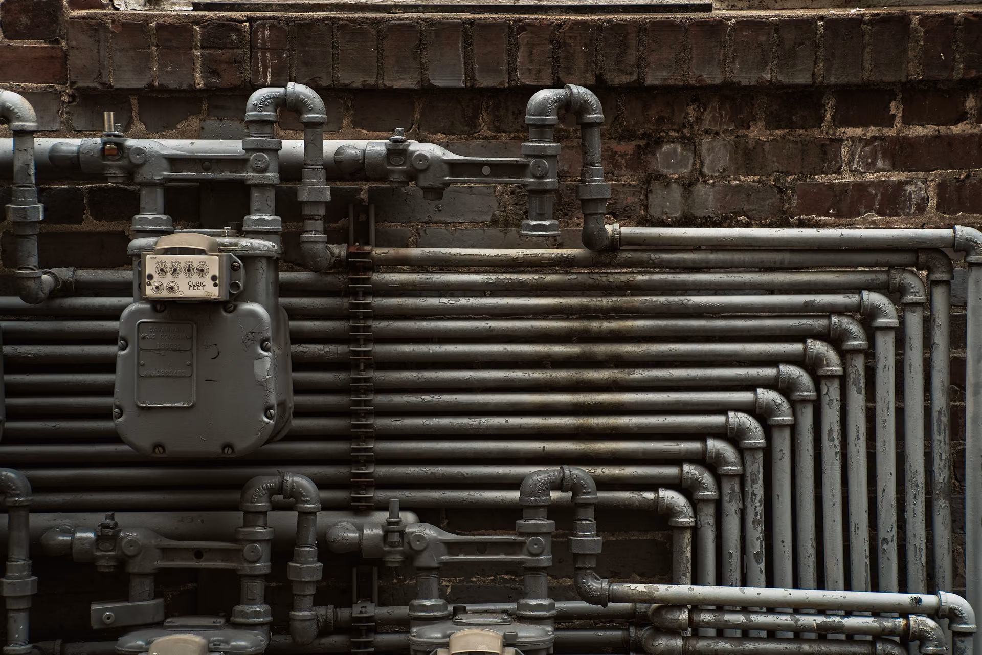 Tubazioni in acciaio e contatore del gas fissati a una parete in mattoni